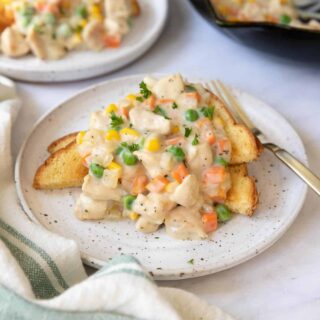 Two plates of chicken pot pie filling over toast.