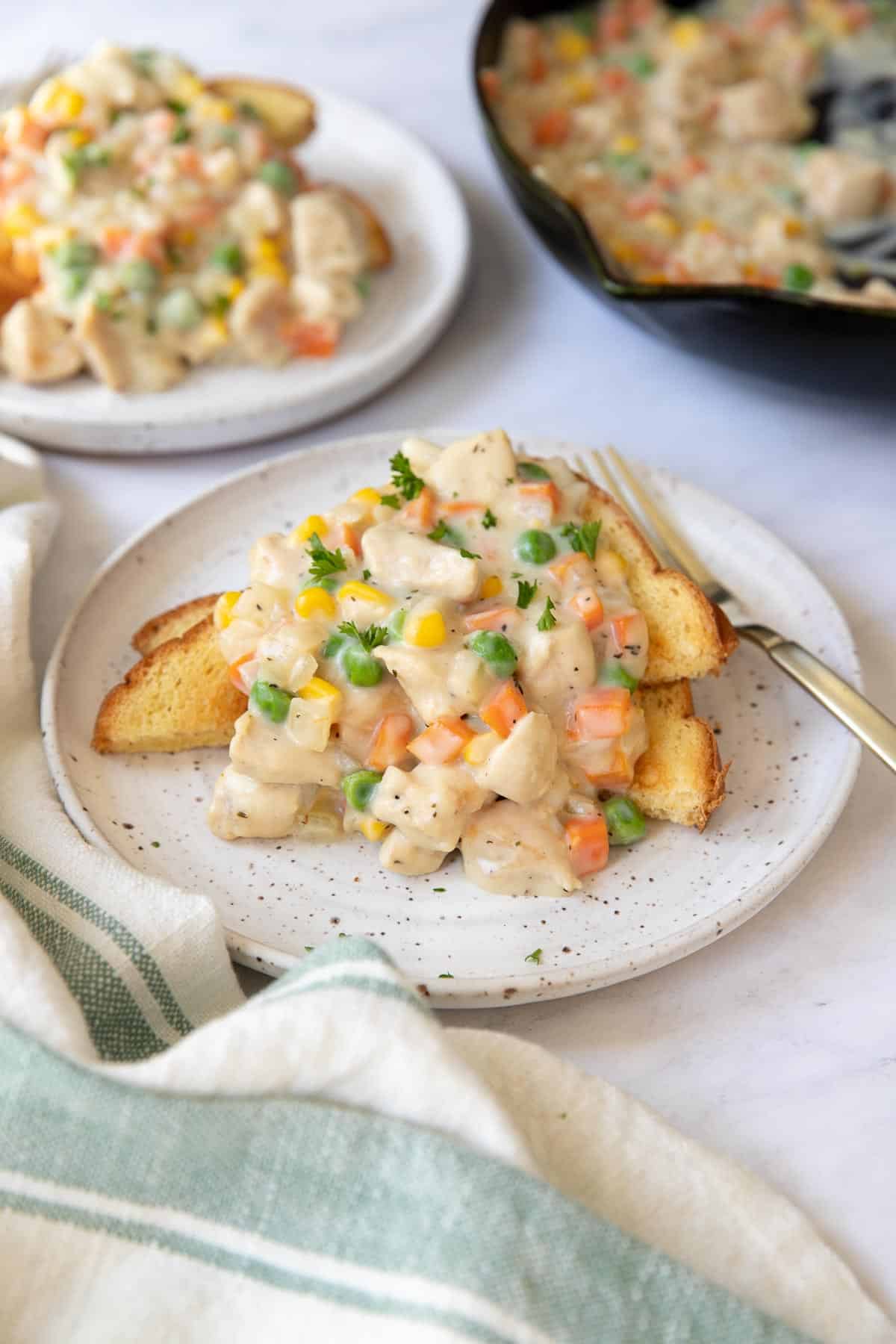 Two plates of chicken pot pie filling over toast.