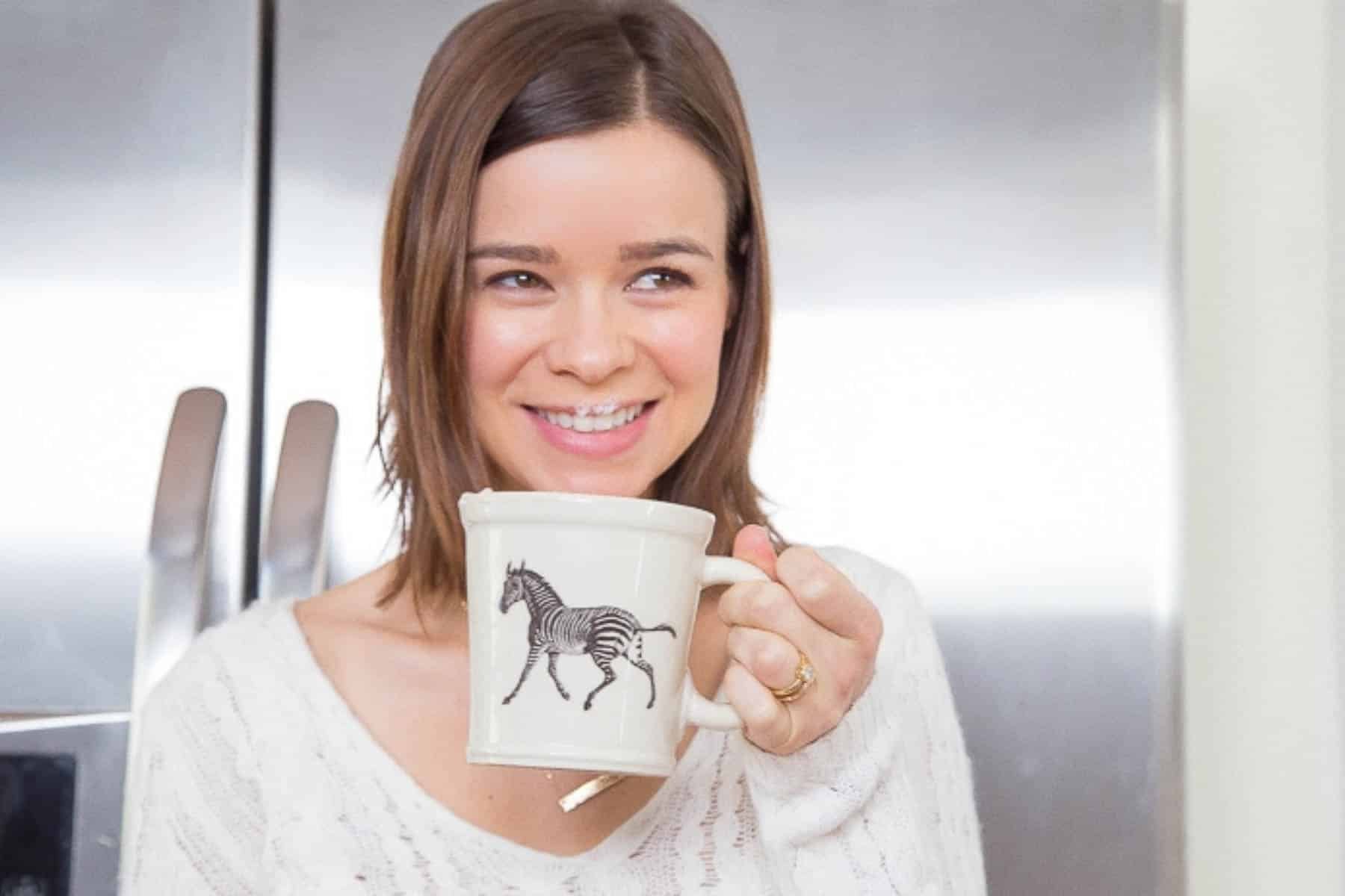 Girl smiling and sipping from mug with zebra on it.