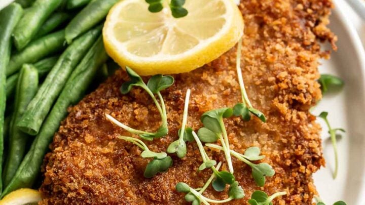Close up of pork schnitzel with green beans on side.
