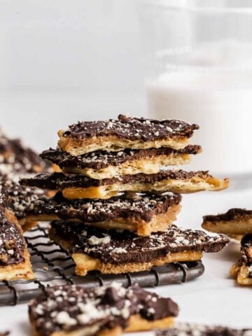 Saltine toffee stacked with milk in background.
