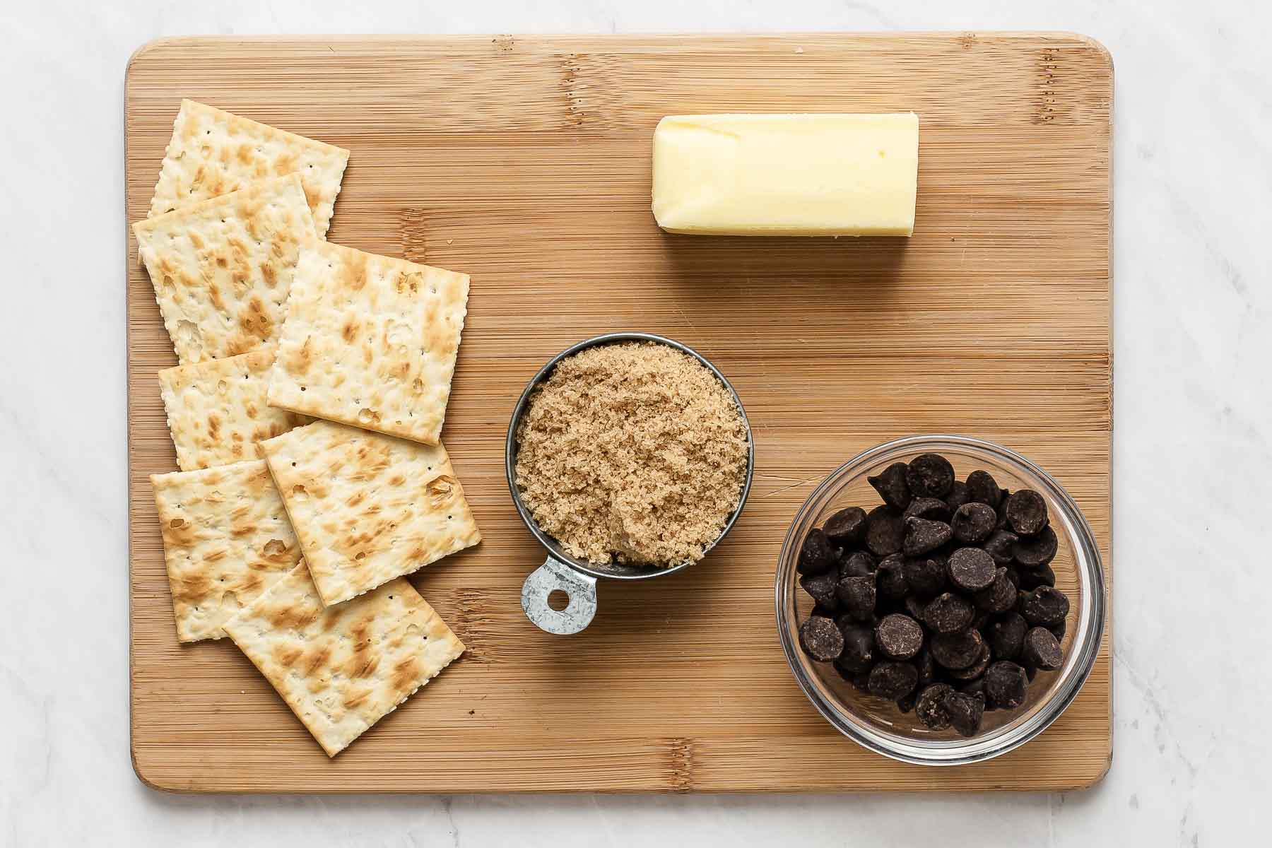 Ingredients for saltine toffee on wooden cutting board.