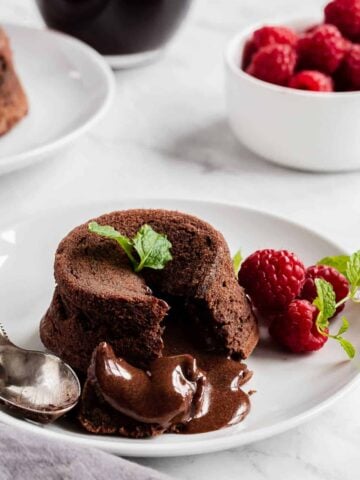 Molten chocolate cake on a plate with raspberries and fresh mint.