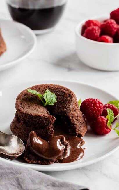 Molten chocolate cake on a plate with raspberries and fresh mint.
