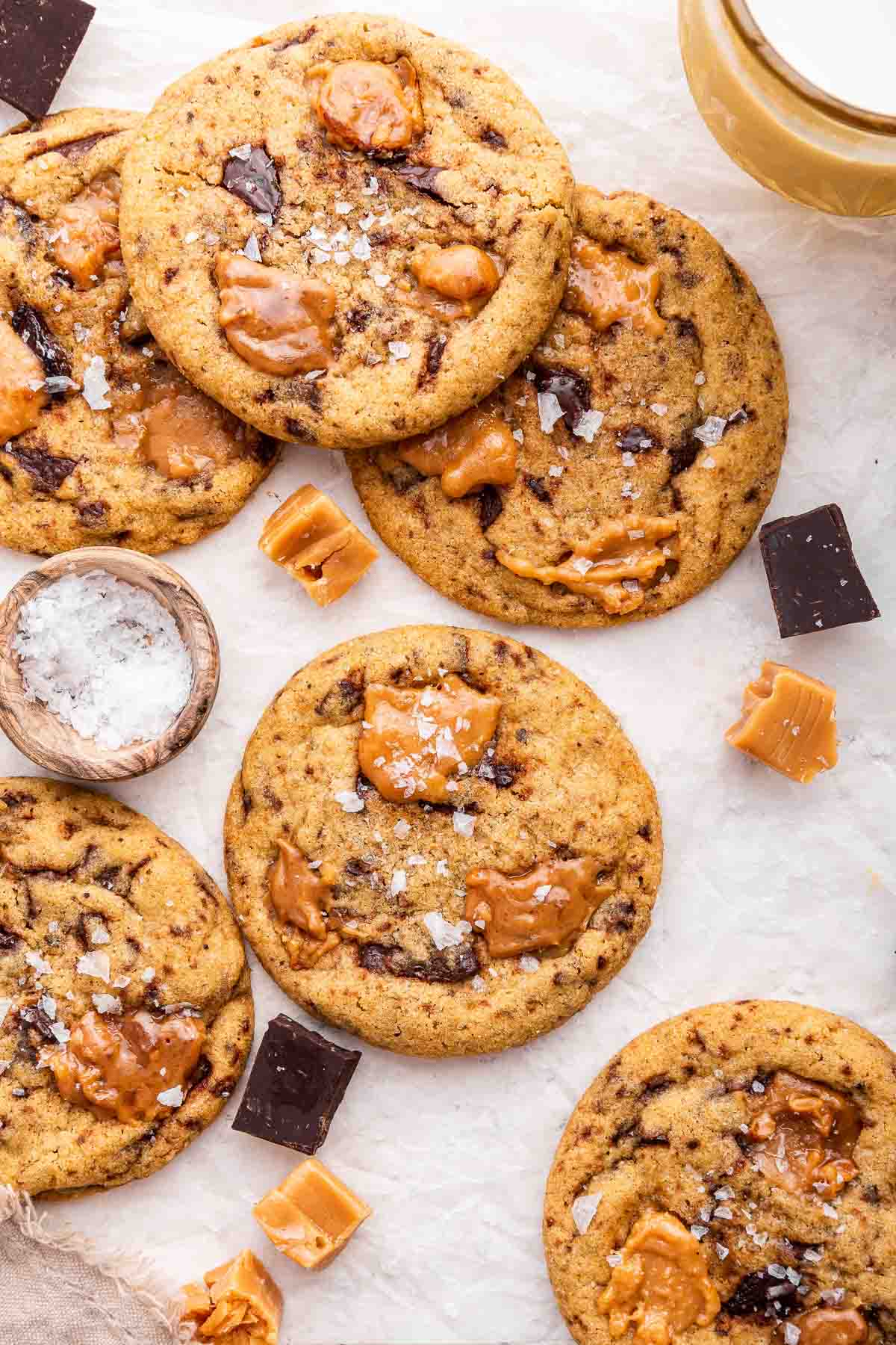 Overhead shot of caramel chocolate chip cookies with bowl of salt on side.