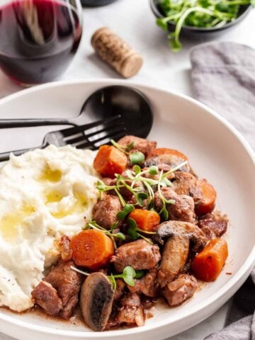 Coq au vin on plate with mashed potatoes.