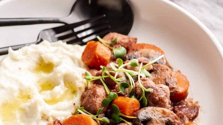 Coq au vin on plate with mashed potatoes.