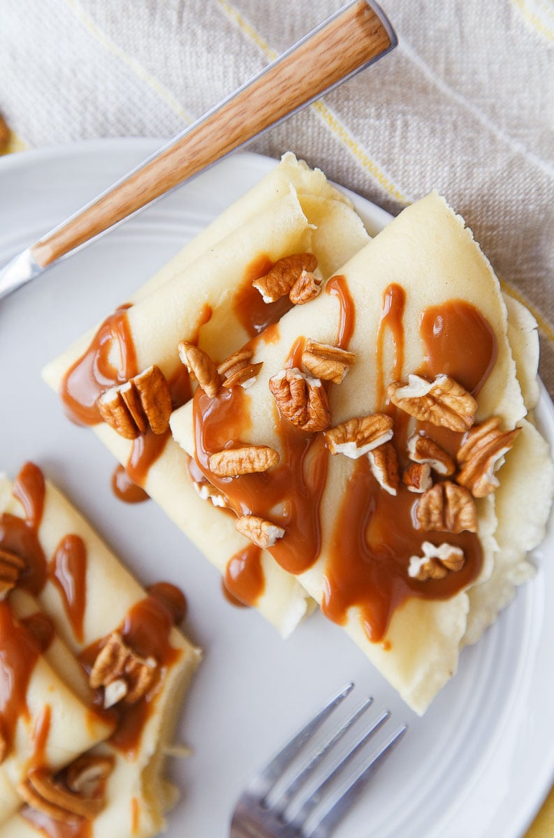 A small batch of crepes with dulce de leche sauce.