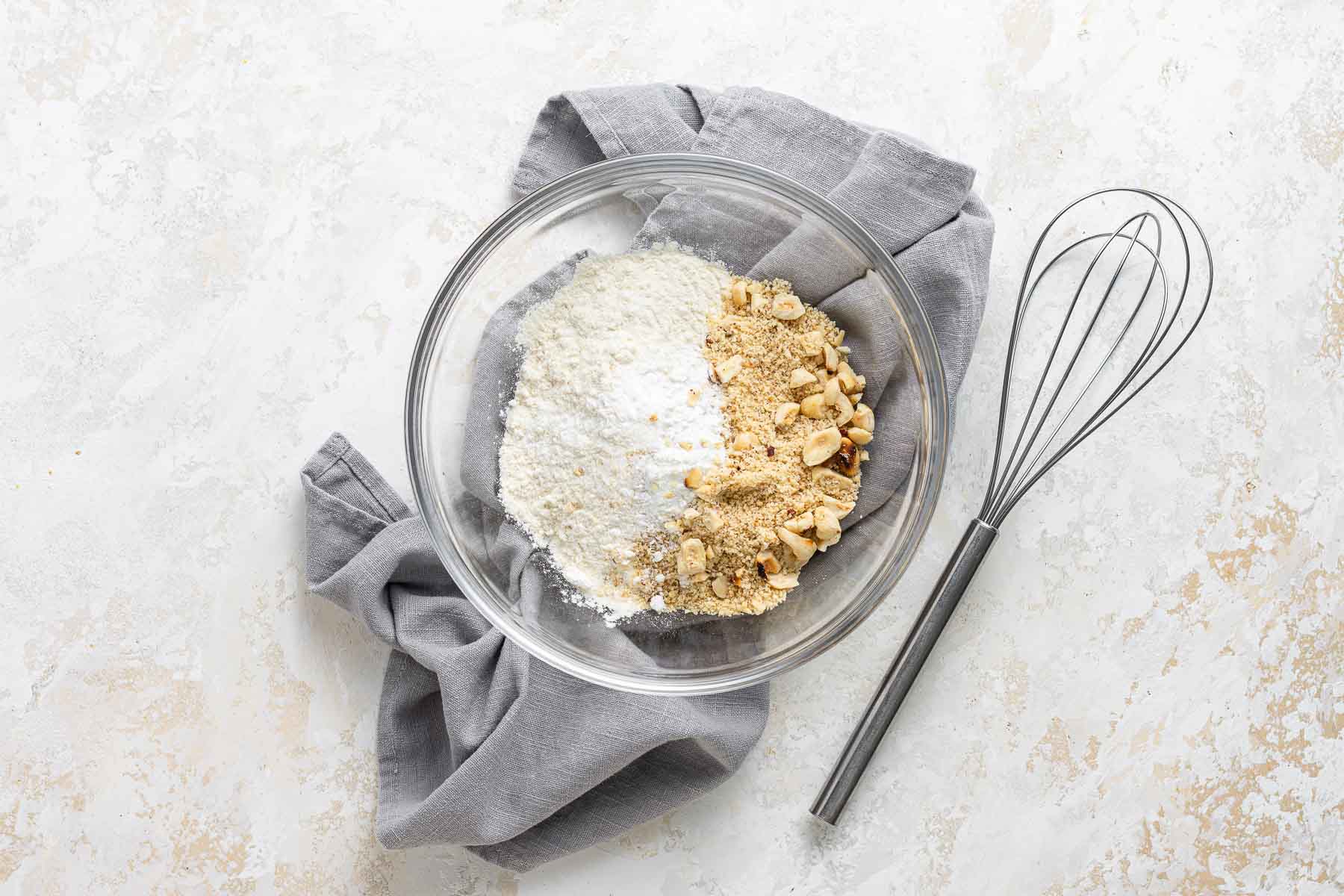 Flour and hazelnut meal in a bowl with whisk.