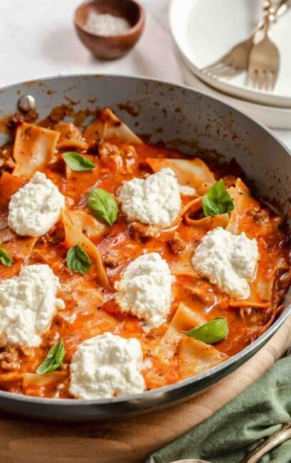 Skillet of lasagna with ricotta dollops.