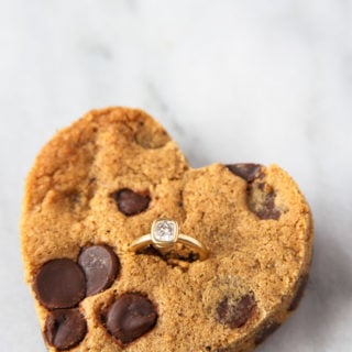 Chocolate Chip cookie cut into heart shape with diamond ring inserted.