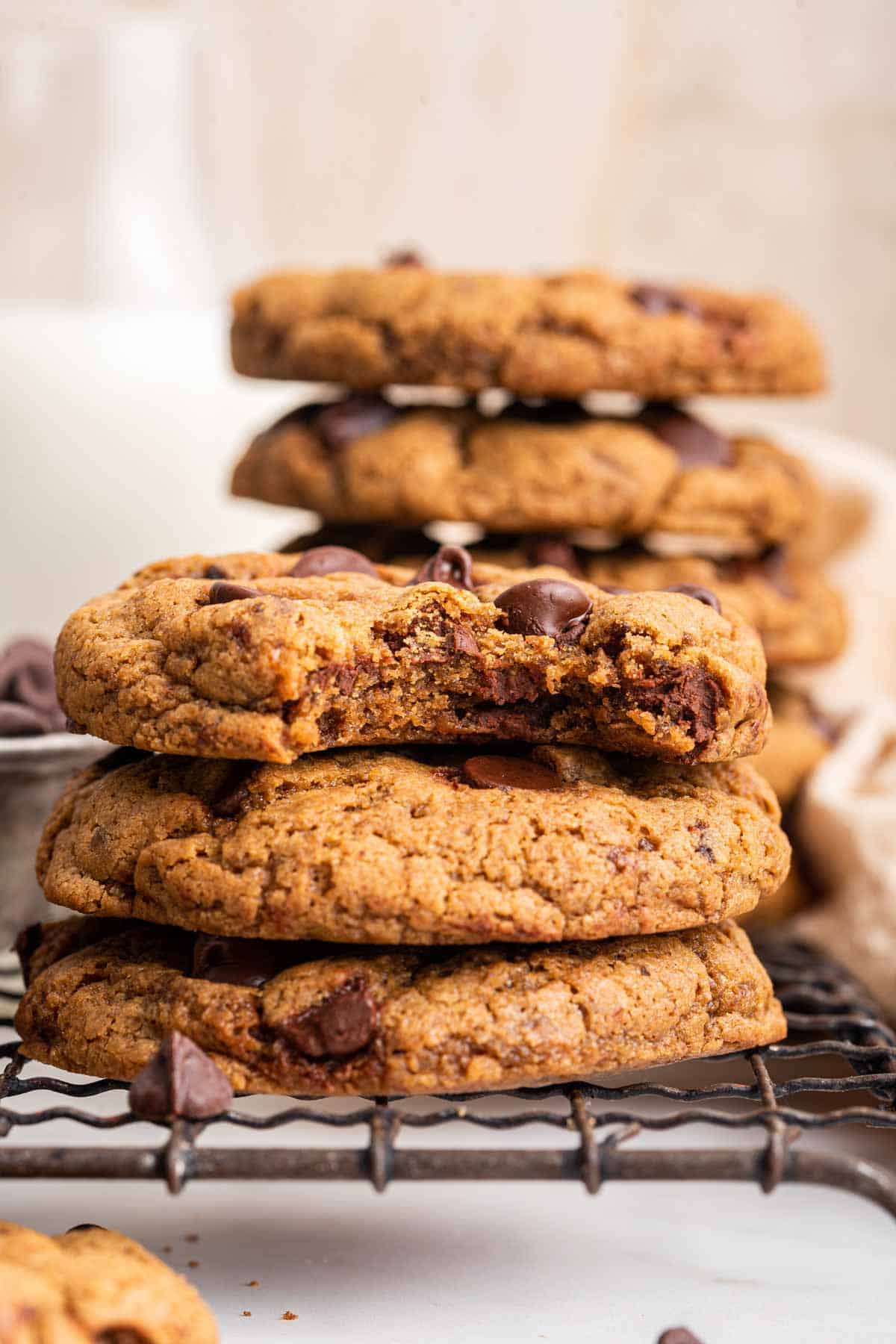 Stack of brown almond butter chocolate chip cookies with a bite missing from the top cookie.