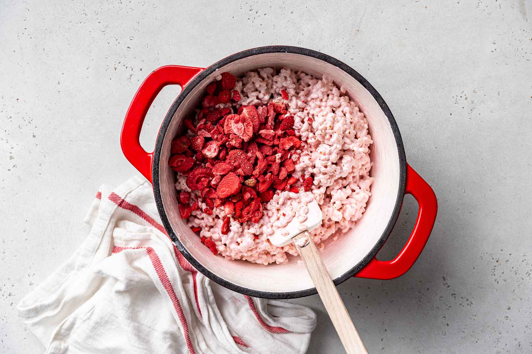Stirring freeze dried strawberries into a pot with pink fluff.