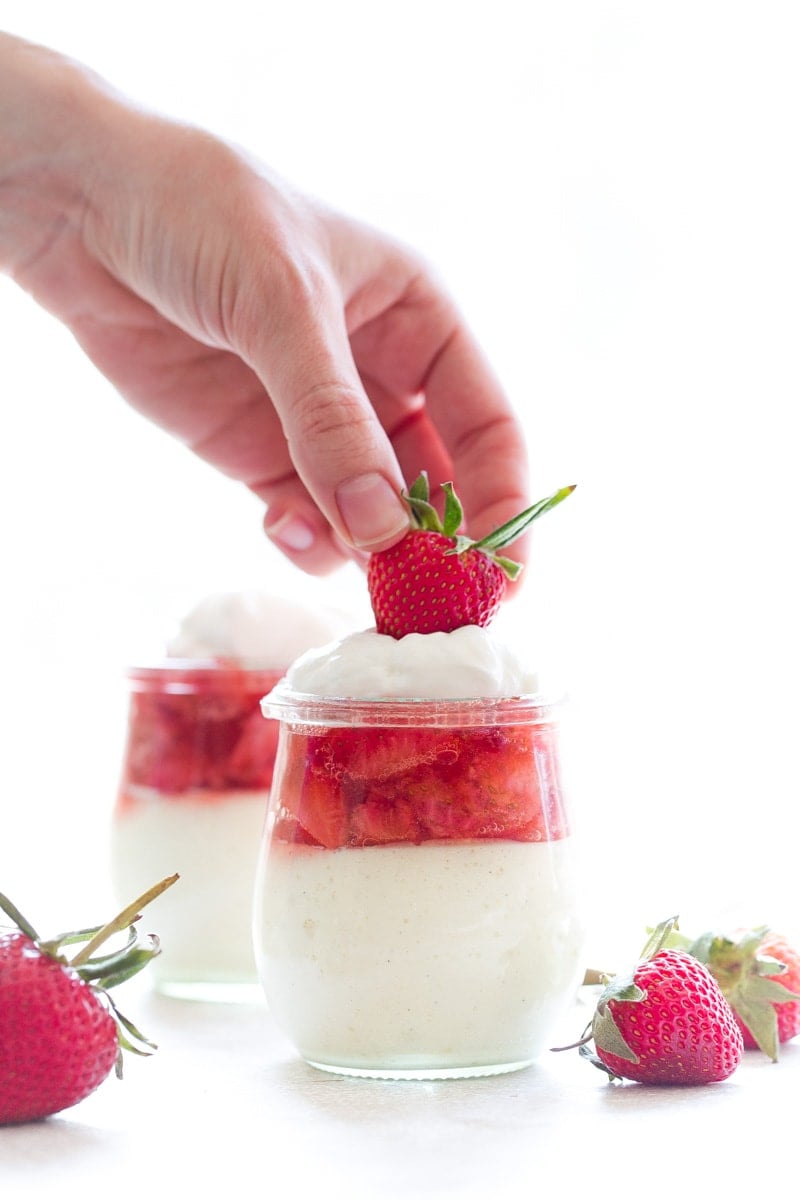 Mini vanilla bean cheesecakes in jars with strawberry sauce