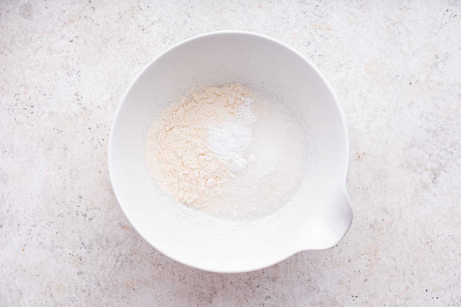 White bowl with flour, sugar and baking powder.
