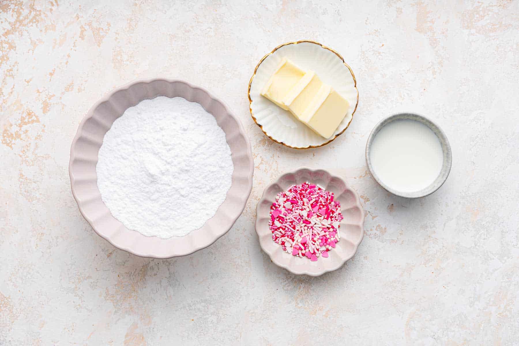 Four white bowls with butter, sugar and sprinkles.
