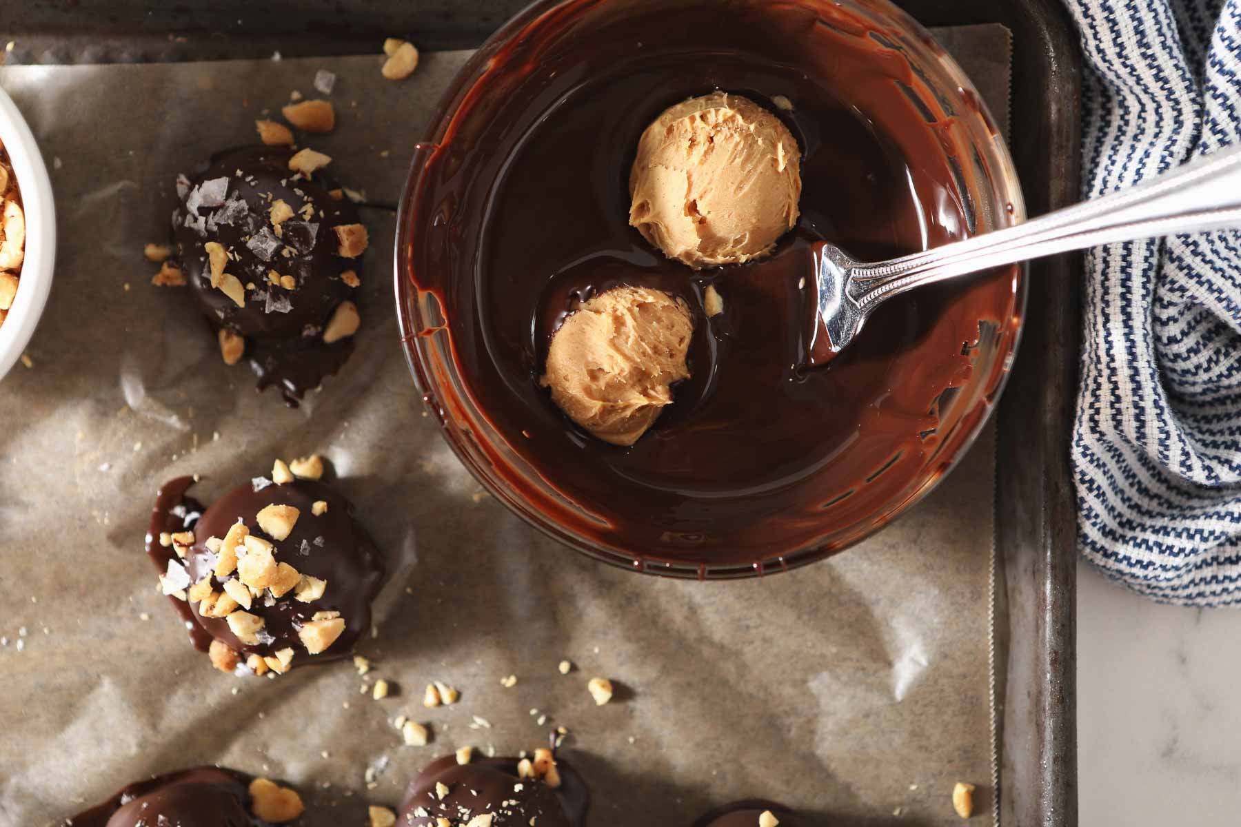 Fork dipping peanut butter truffles in a bowl of melted chocolate.