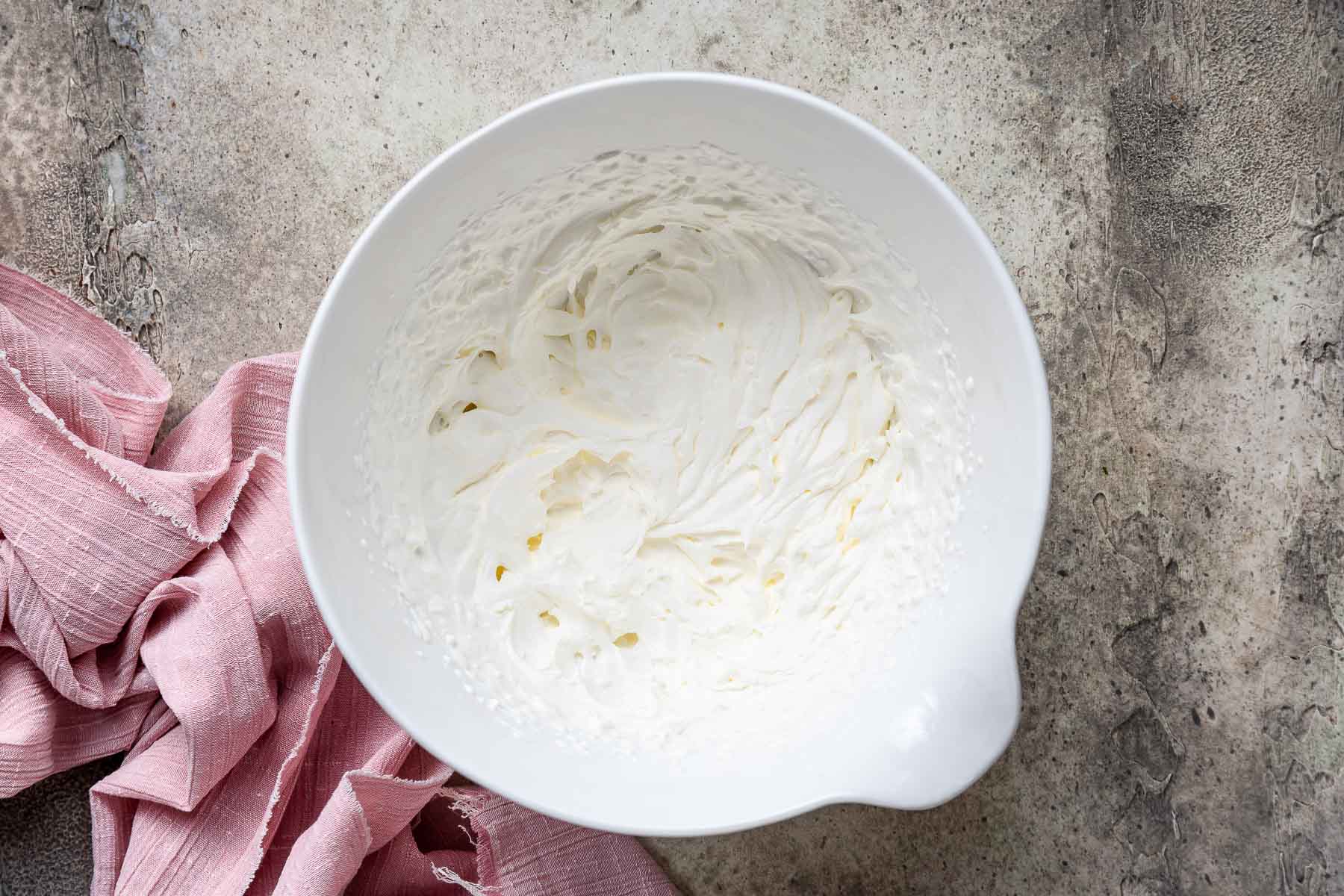 Freshly whipped cream in white bowl.