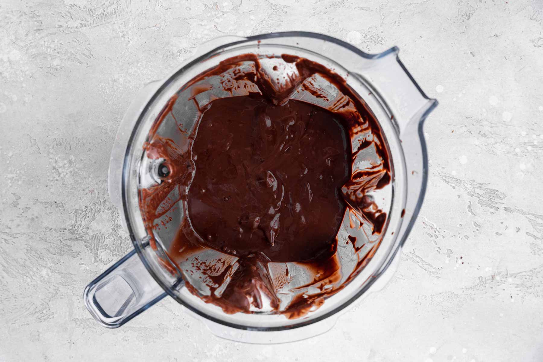 Shiny melted chocolate in a blender with the lid off.