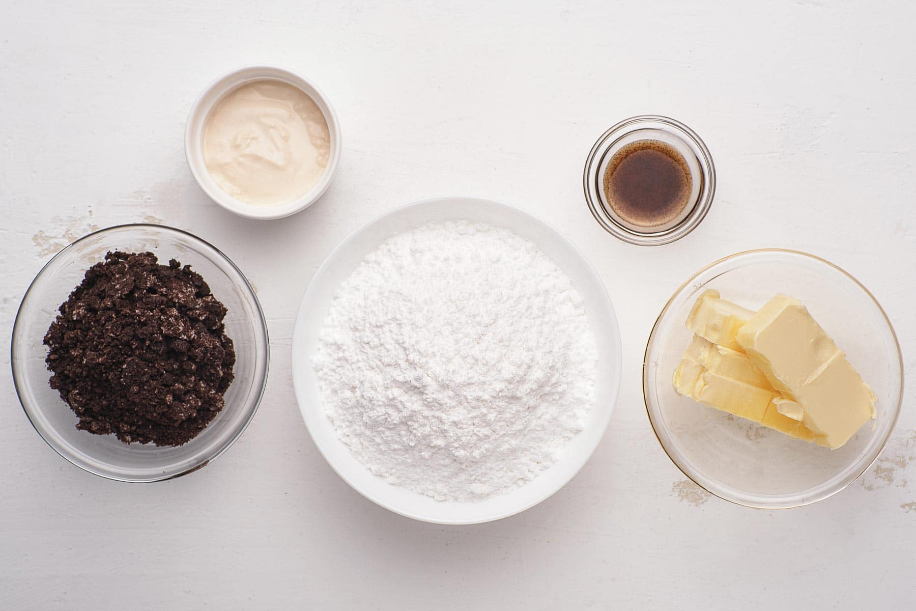 Ingredients for cookies and cream frosting in small bowls.
