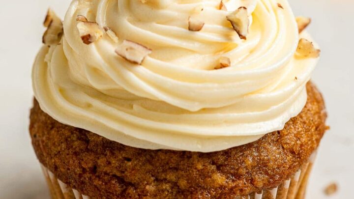 Up close image of carrot cake with cream cheese frosting and pecans.