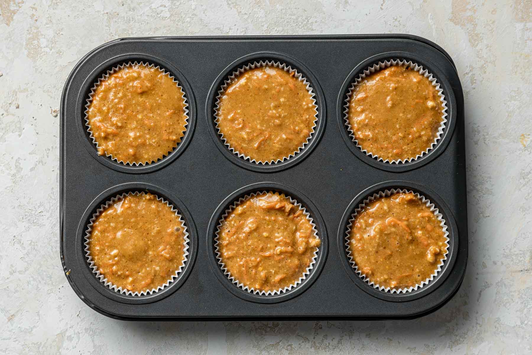 Raw carrot cake cupcakes in muffin pan.