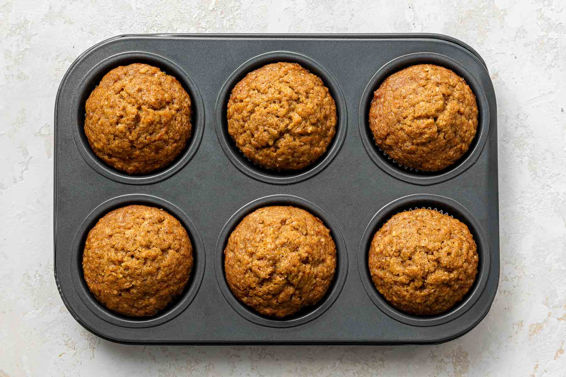 Orange cupcakes cooling in muffin pan.