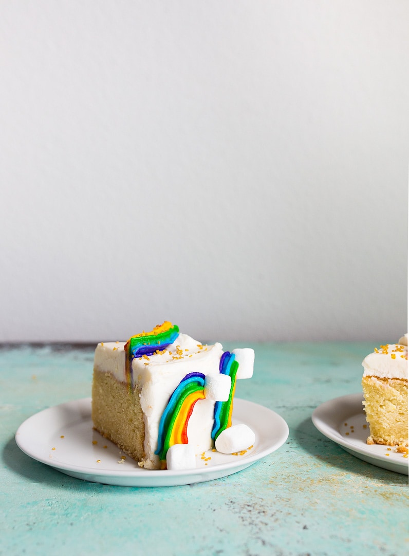 Rainbow Cake Recipe: mini rainbow cake with rainbow buttercream, marshmallow clouds and gold sprinkles. Perfect first birthday cake or rainbow baby smash cake.