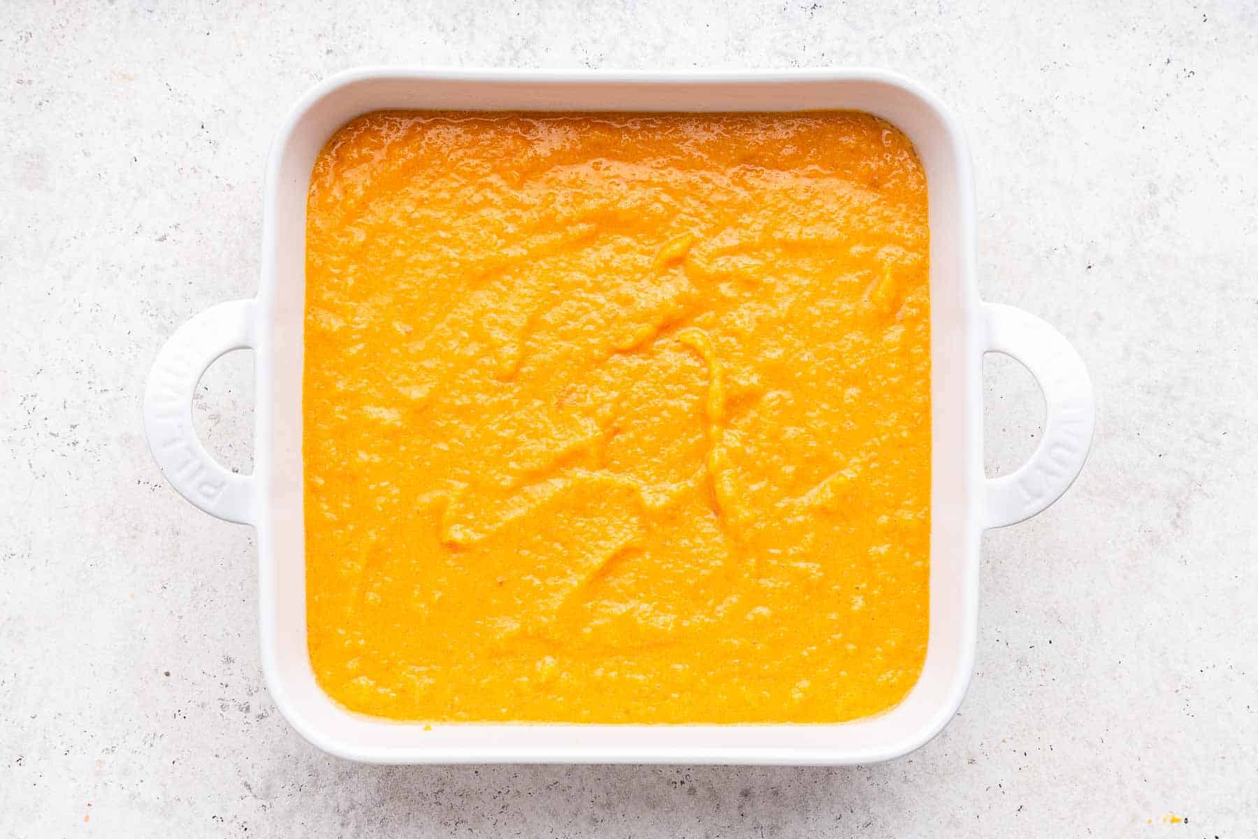 Bright orange batter in a white square casserole dish.