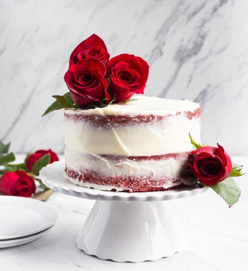 Small 6 inch red velvet cake with roses on top.