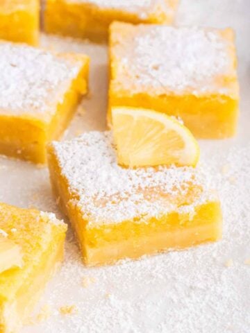 Vertical shot of sliced lemon bars with powdered sugar and lemon square on top.