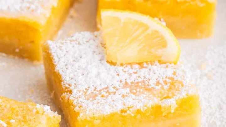 Vertical shot of sliced lemon bars with powdered sugar and lemon square on top.