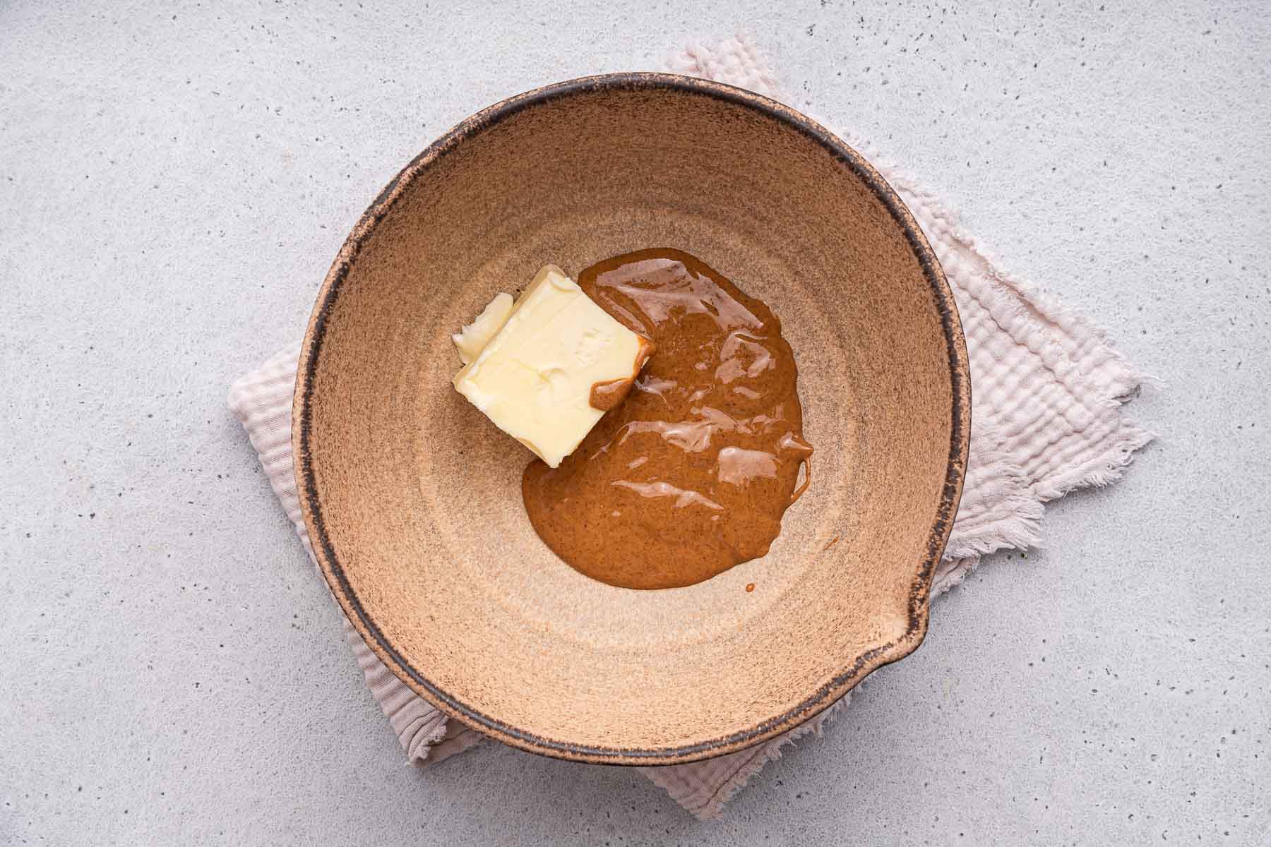 Almond butter and butter in a brown mixing bowl.