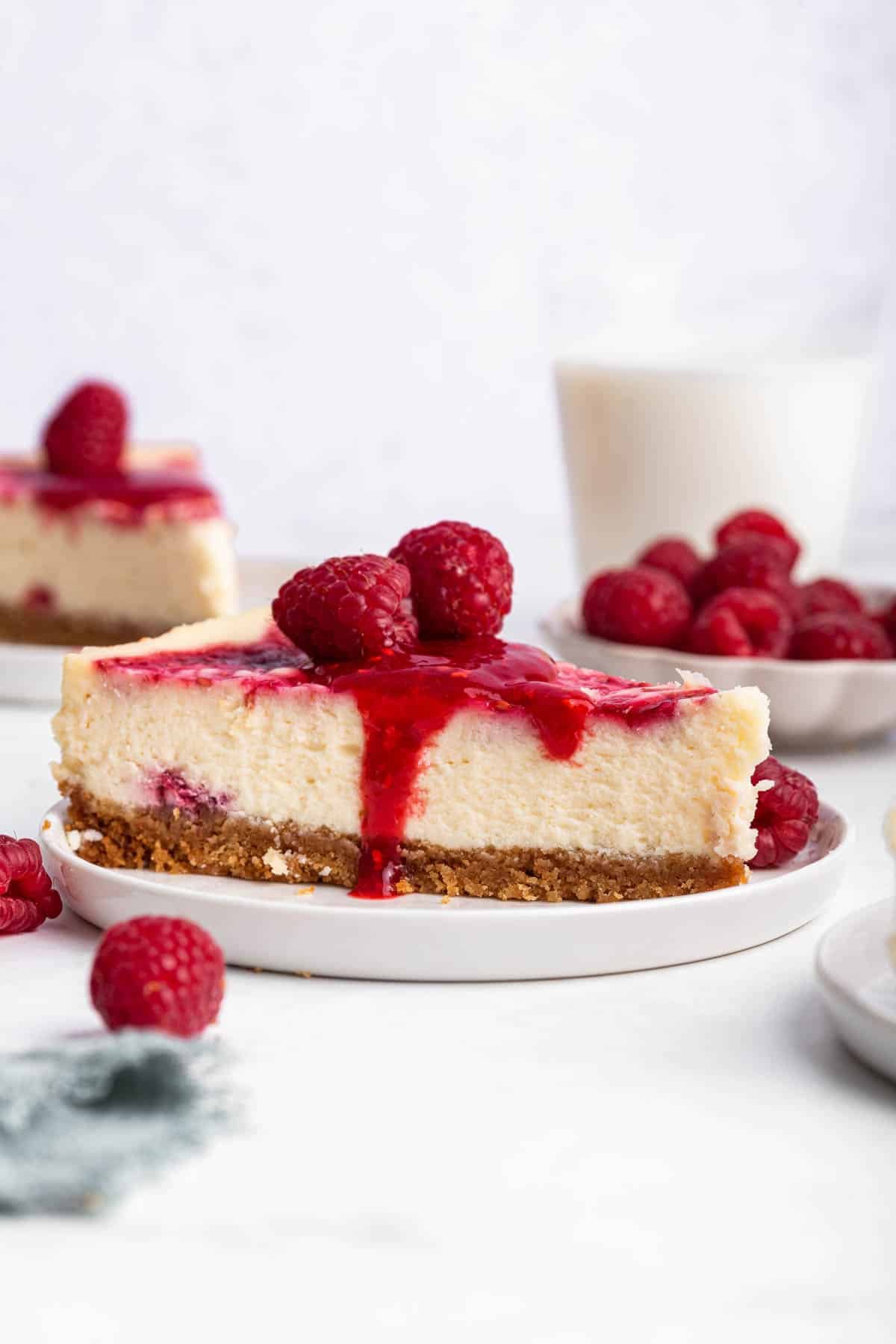 Slice of dessert with graham cracker crust and red berry sauce on top.