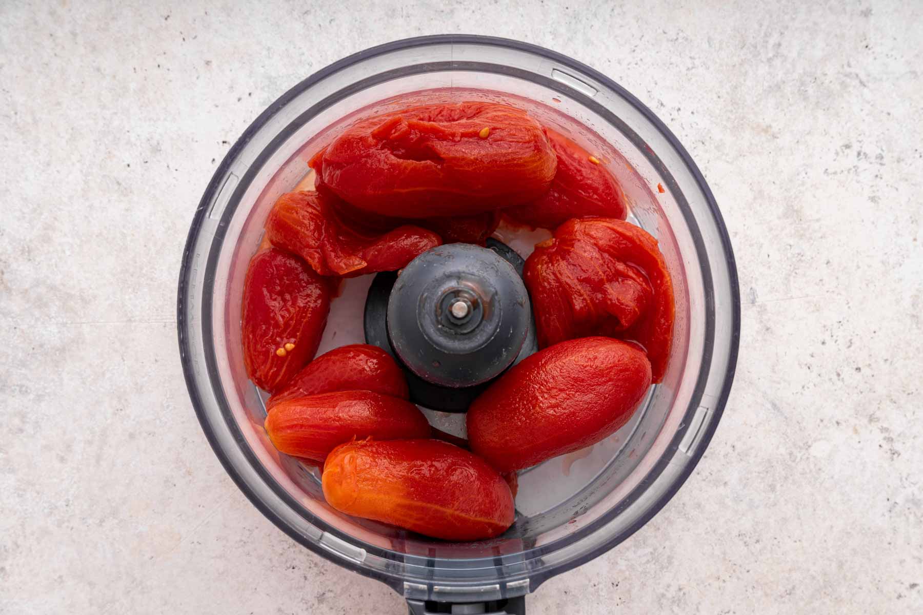 Canned tomatoes in the bowl of a food processor.