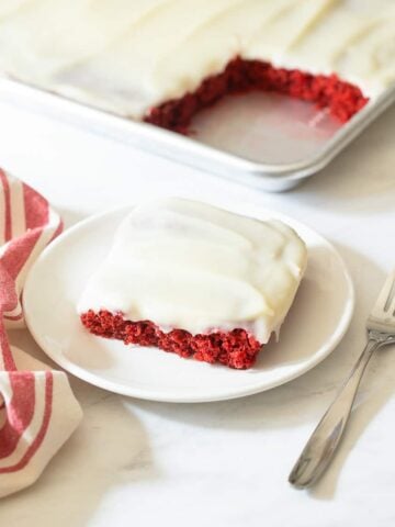 Slice of red velvet sheet cake on plate.
