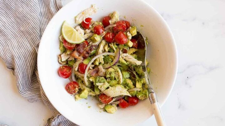 mixed vegetable salad with chicken in a bowl with a spoon