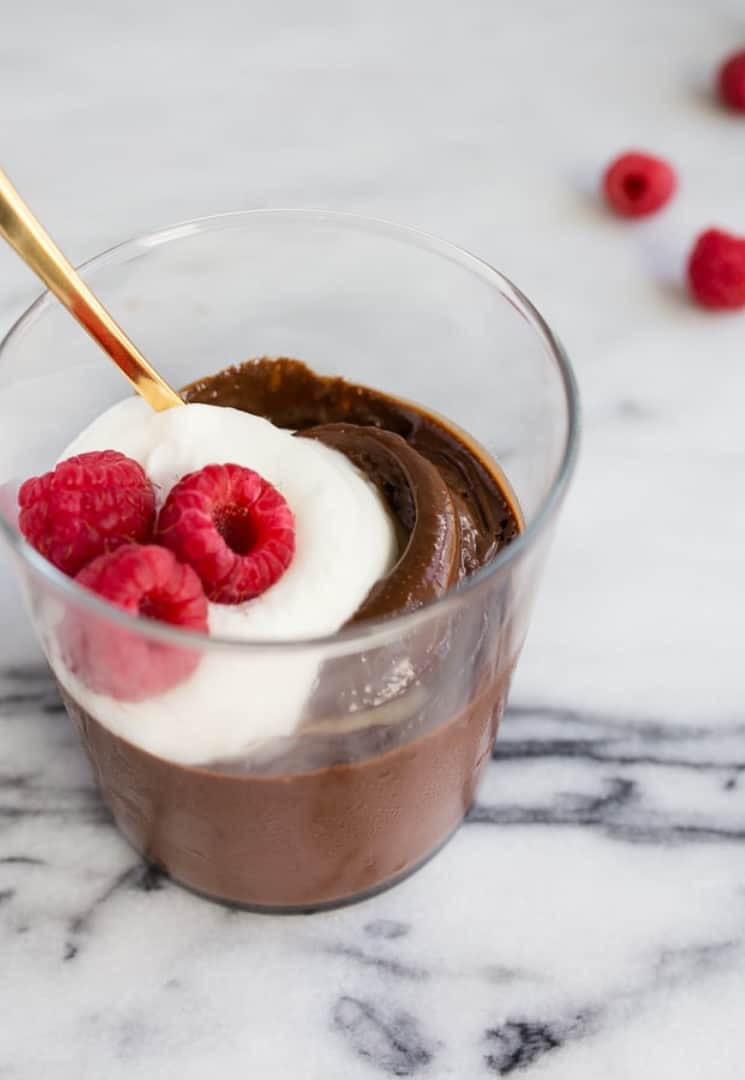 glass of chocolate pudding with whipped cream and fresh raspberries