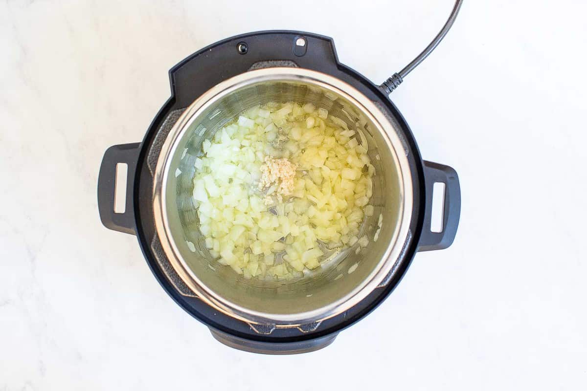Instant pot with garlic and onions sautéing.