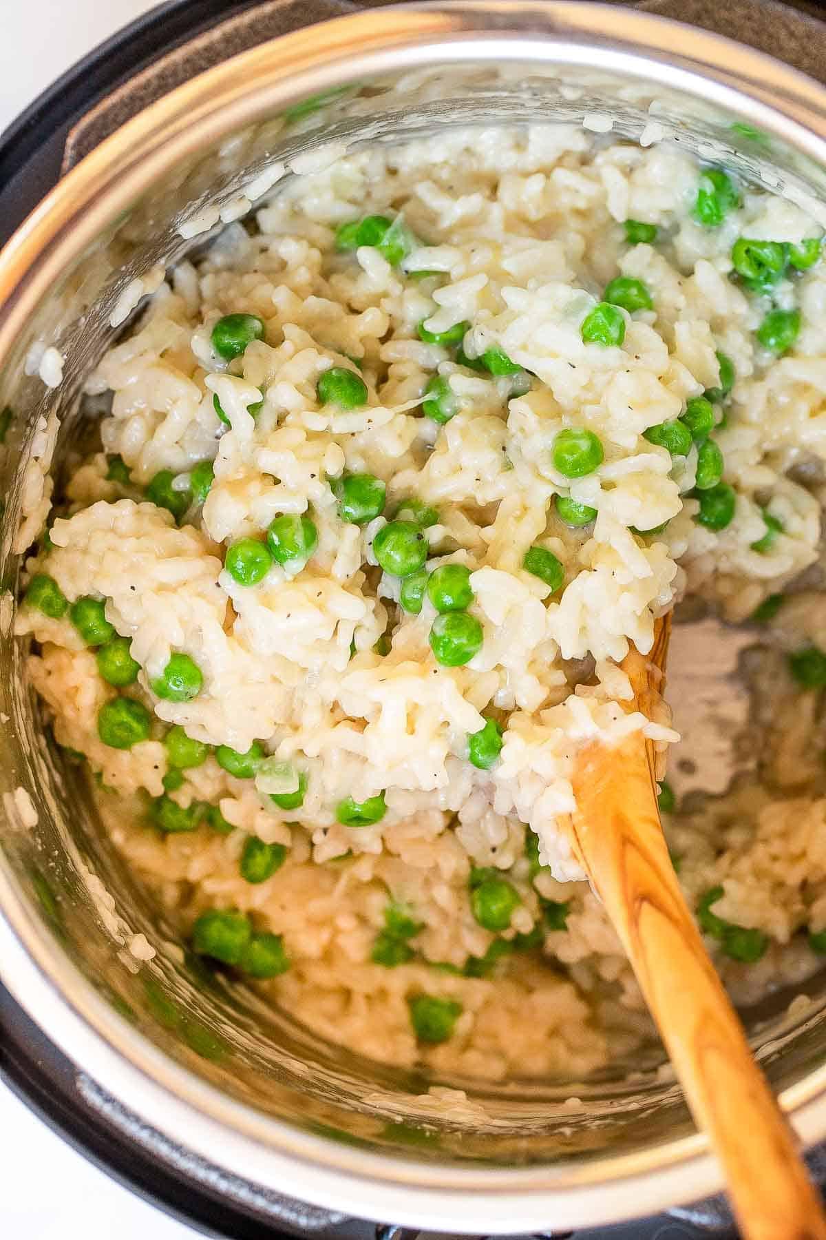 Risotto with peas in the instant pot mini with a wooden spoon.