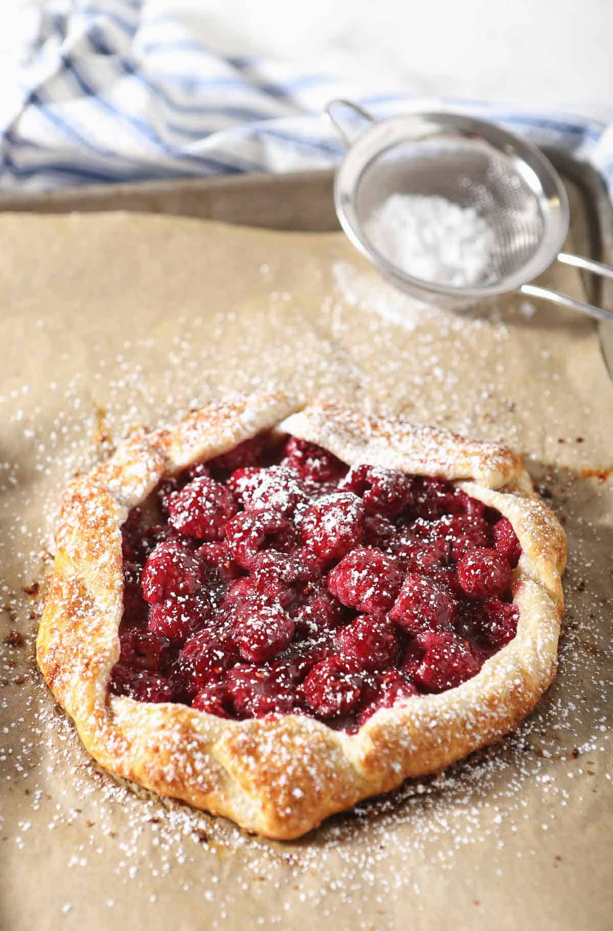 Small fresh raspberry galette dusted with powdered sugar.