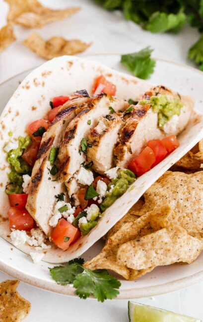 Soft tortilla with sliced chicken, guacamole and tomatoes.