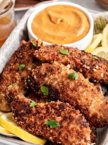 Pile of buttermilk chicken tenders with orange sauce in background.