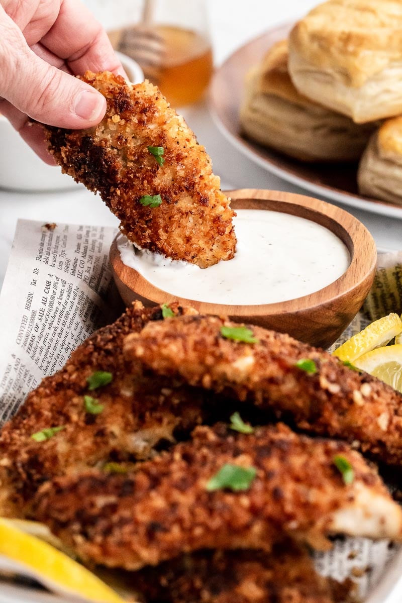 Buttermilk fried chicken tender being dipped in ranch.