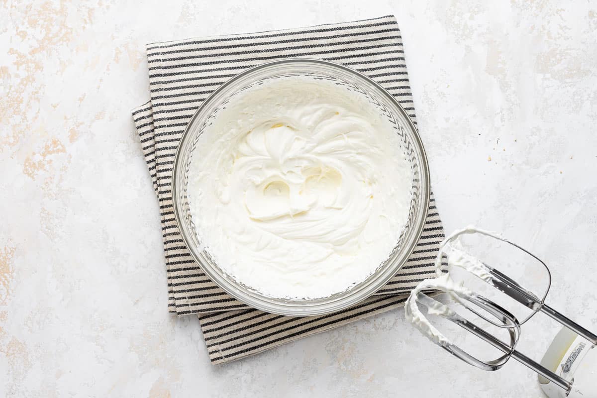 Freshly whipped cream in a clear bowl with beaters.