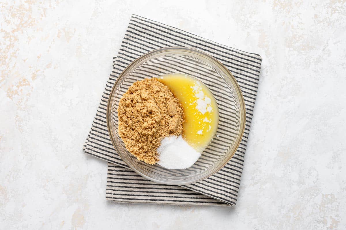 Graham cracker crust ingredients in a clear bowl with kitchen towel.