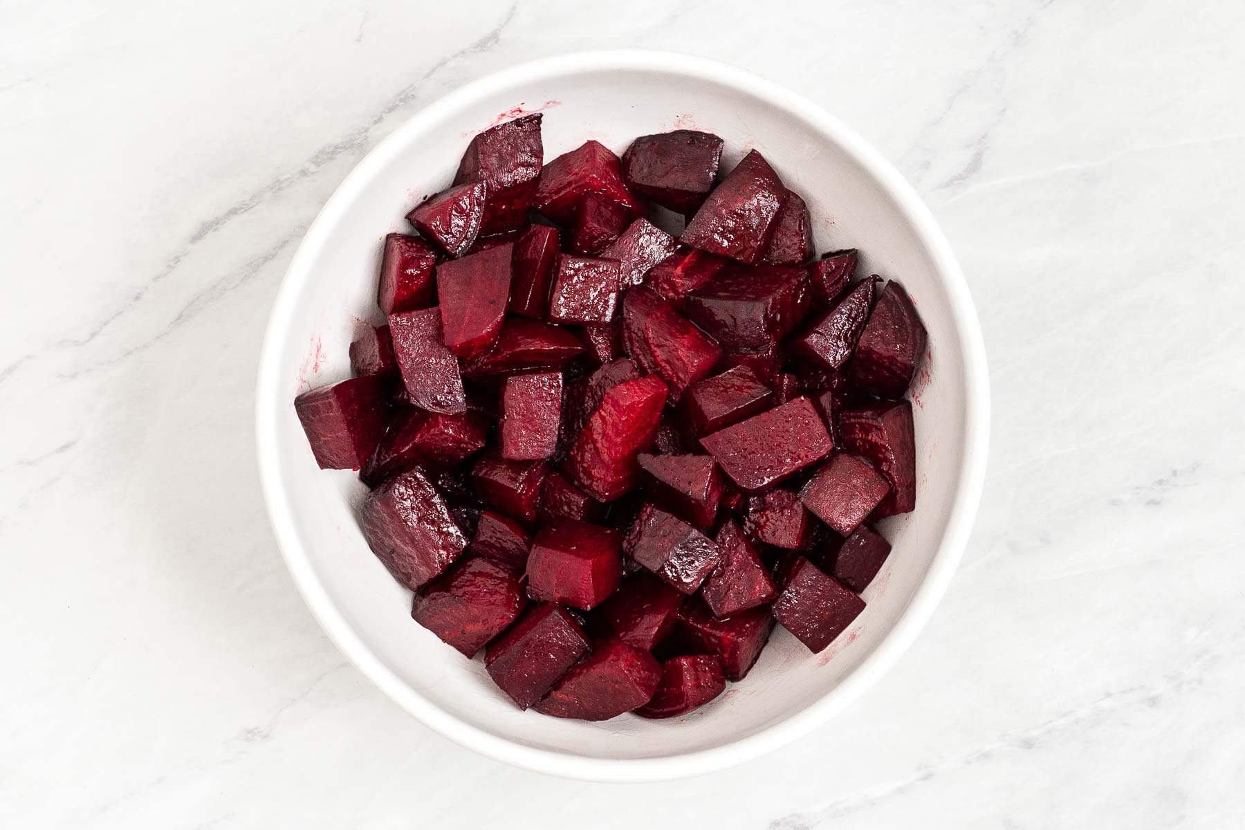 Cooked beets in a white bowl.