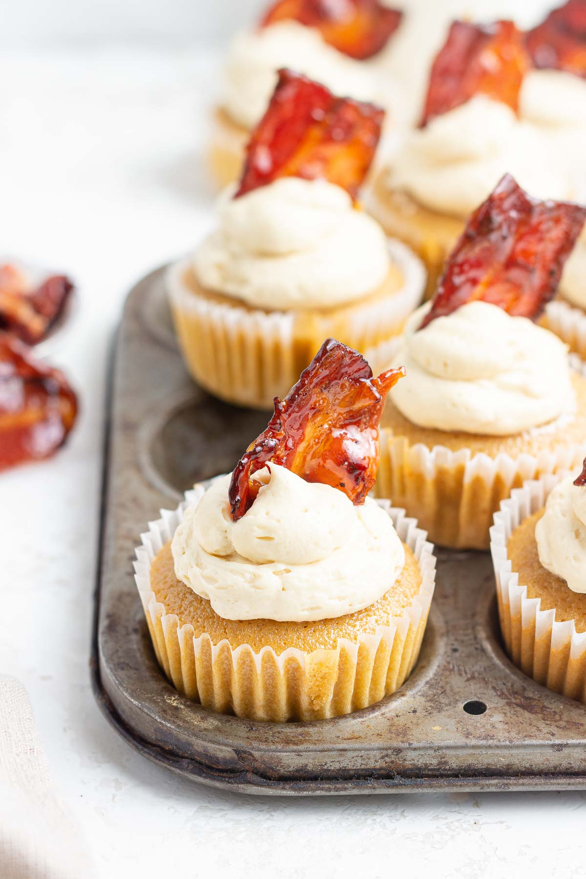 Close up of maple bacon cupcakes with bacon piece on top.
