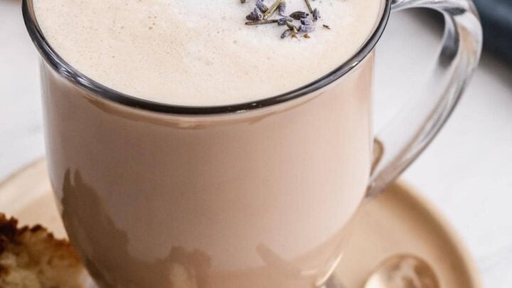 London Fog drink in a clear glass mug with lavender buds on top.