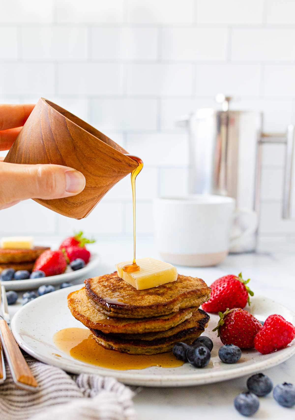 Syrup being poured on a pancake stack.